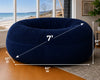 Navy bean bag chair with dimensions in a room with large windows showing a beach view.